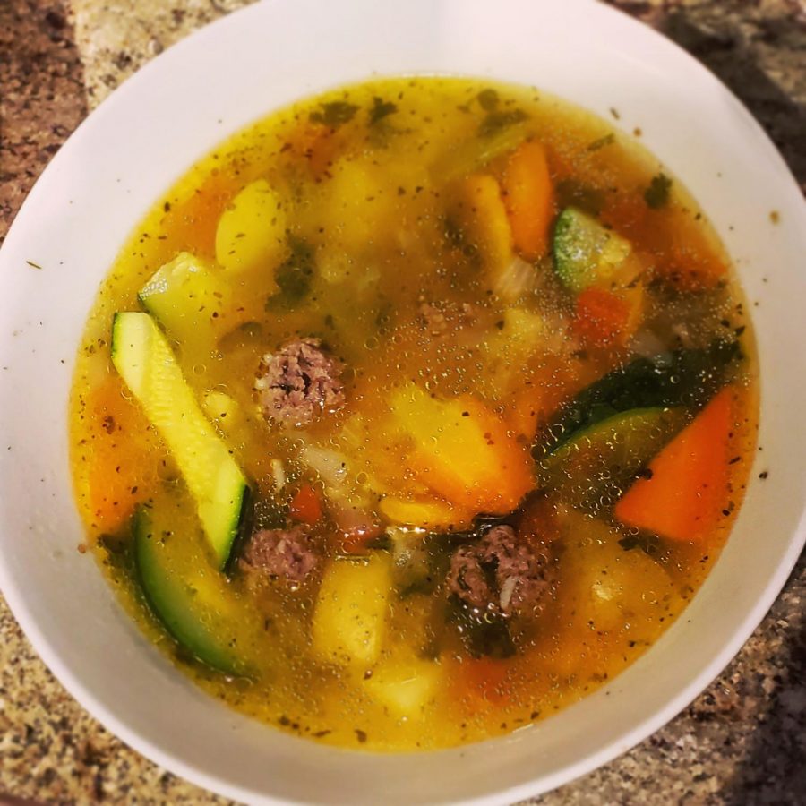 A bowl of albondigas soup, hot and ready to eat.