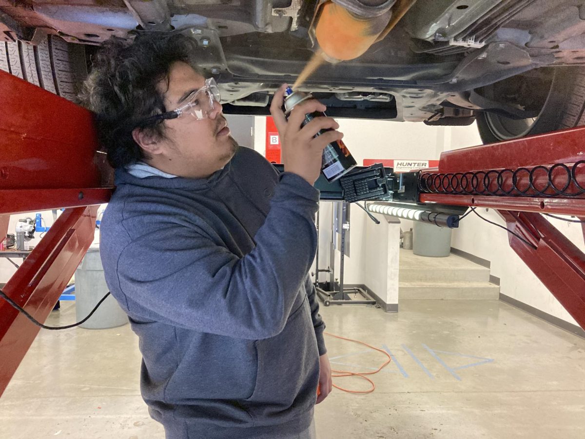 A student sprays a catalytic converter with a bright-colored paint to prevent the auto part from being stolen. (Jeffrey Shirts)